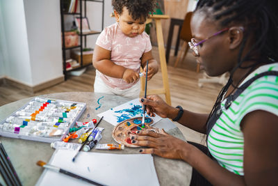 Side view of girl painting on table