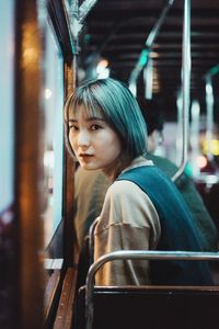 Close-up portrait of young woman standing in bus