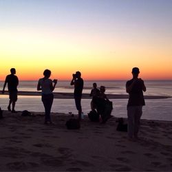 Silhouettes of people on beach at sunset