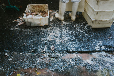 Low section of working man standing on wet ground with fish scraps around him