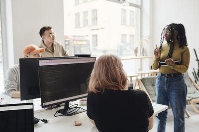 Female programmer giving presentation to colleagues during meeting in office