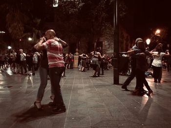 People walking on illuminated street at night