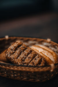 Wicker basket with fresh grain bread and pastries on the wooden table. vertical