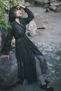 Low angle view of young woman standing against rock