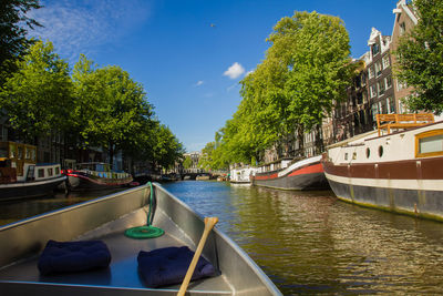 Boats moored on river in city against sky