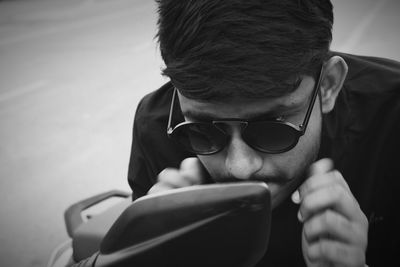 Young man looking into side-view mirror of motorcycle
