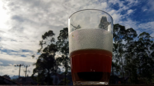 Close-up of beer glass against sky
