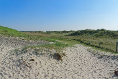 Scenic view of sandy landscape against clear blue sky