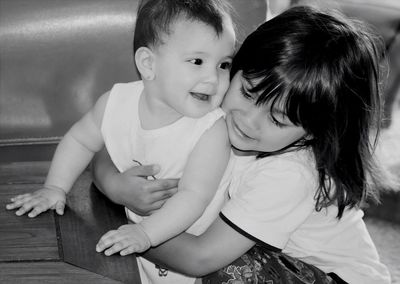 Girl hugging brother by table
