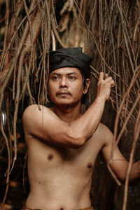 Portrait of young man standing against tree