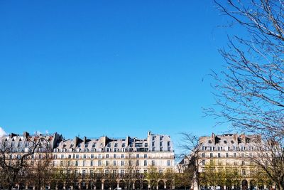 Low angle view of buildings against clear blue sky on sunny day