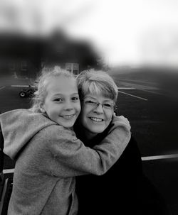 Portrait of smiling grandmother and granddaughter embracing at playground