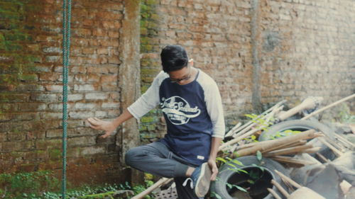 Full length of young man sitting on wall