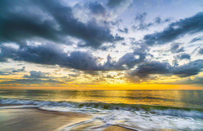 Scenic view of sea against dramatic sky during sunset