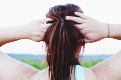 Rear view of woman with hands hair