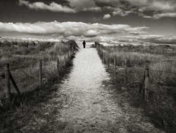 View of field against cloudy sky