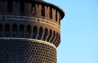 Low angle view of tower castello sforzesco against clear blue sky