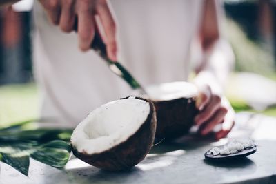 Midsection of man removing coconut on table