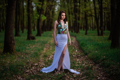 Full length of woman standing on field in forest