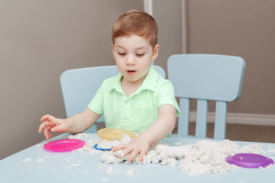 Boy looking away while sitting on table at home