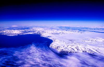 Aerial view of snowcapped mountains against blue sky