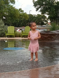 Full length of girl with umbrella standing on rainy day