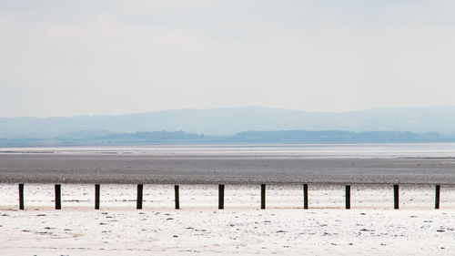 Wooden posts on beach against sky