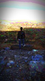 Man standing on land against sky during sunset