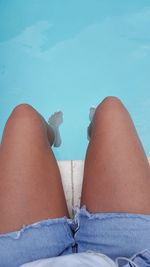 Low section of young woman sitting at poolside