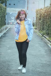 Portrait of smiling young woman standing on footpath