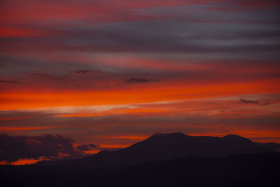 Scenic view of silhouette mountains against romantic sky at sunset