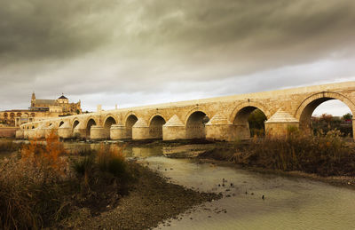 Arch bridge over river against sky