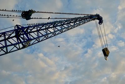 Low angle view of crane at construction site against sky