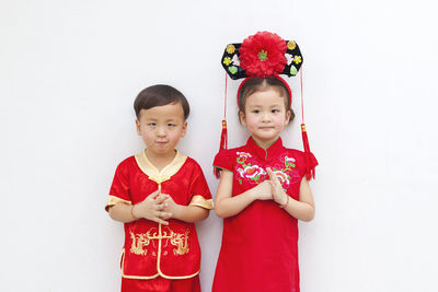 Portrait of cute girl standing against red wall