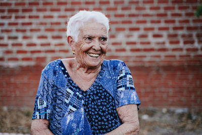 Portrait of a smiling young man against brick wall