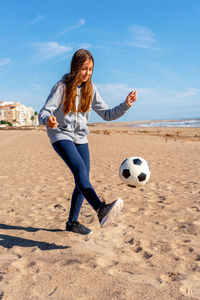 Low section of man playing soccer at beach