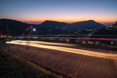 Light trails on road against sky at night