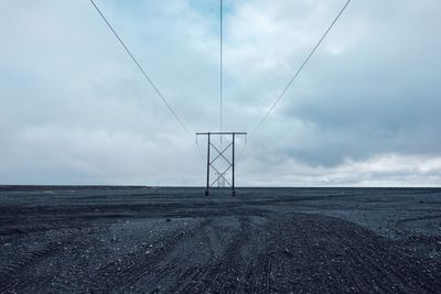 Electricity pylons on land against sky