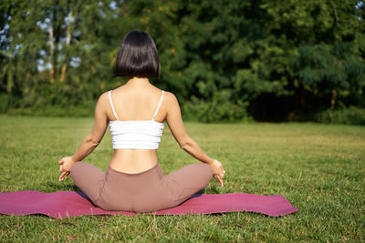 Side view of woman sitting on grassy field