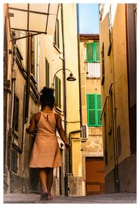 Full length of young woman standing against building