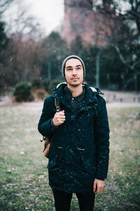 Young man wearing warm clothing standing in park during winter