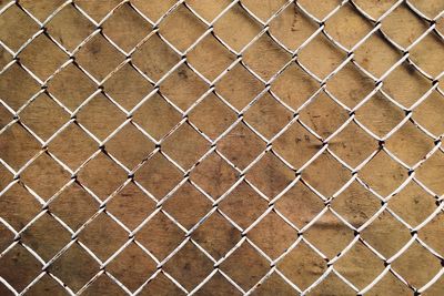 Full frame shot of chainlink fence against wall