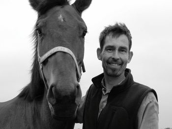 Portrait of smiling man with horse against sky