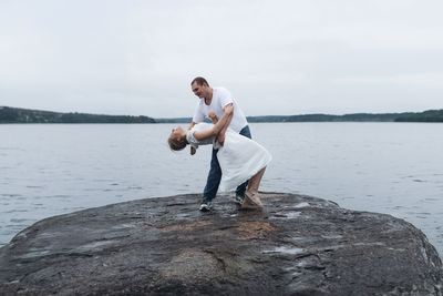 Rear view of man standing on rock by lake