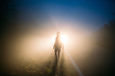 Silhouette man walking against sun during sunset