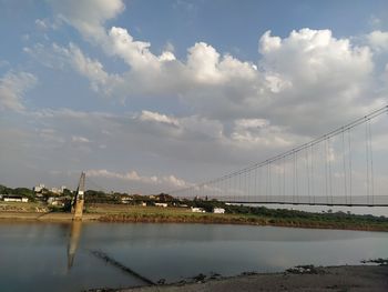 Bridge over river against cloudy sky