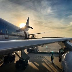 Airplane on airport runway against sky during sunset