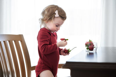 Cute little caucasian blonde baby girl,toddler, pretty,adorable infant eating strawberry