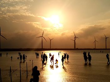 Silhouette people by sea against sky during sunset