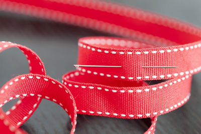 Close-up of red ribbon and sewing needle on table